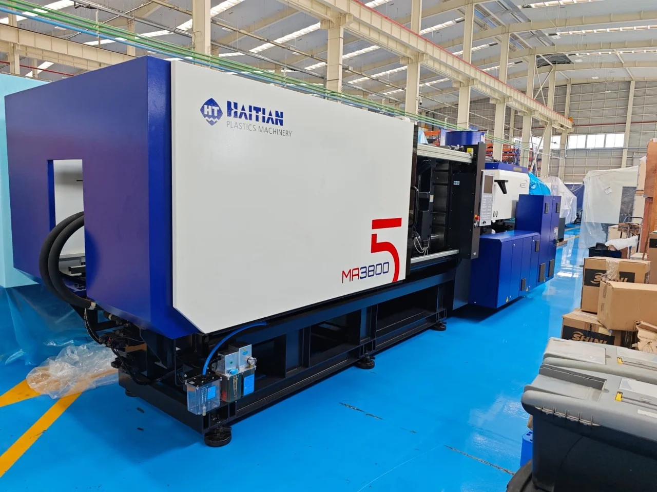Máquina de inyección de plástico azul y blanca en un área industrial, con marca Haitian visible