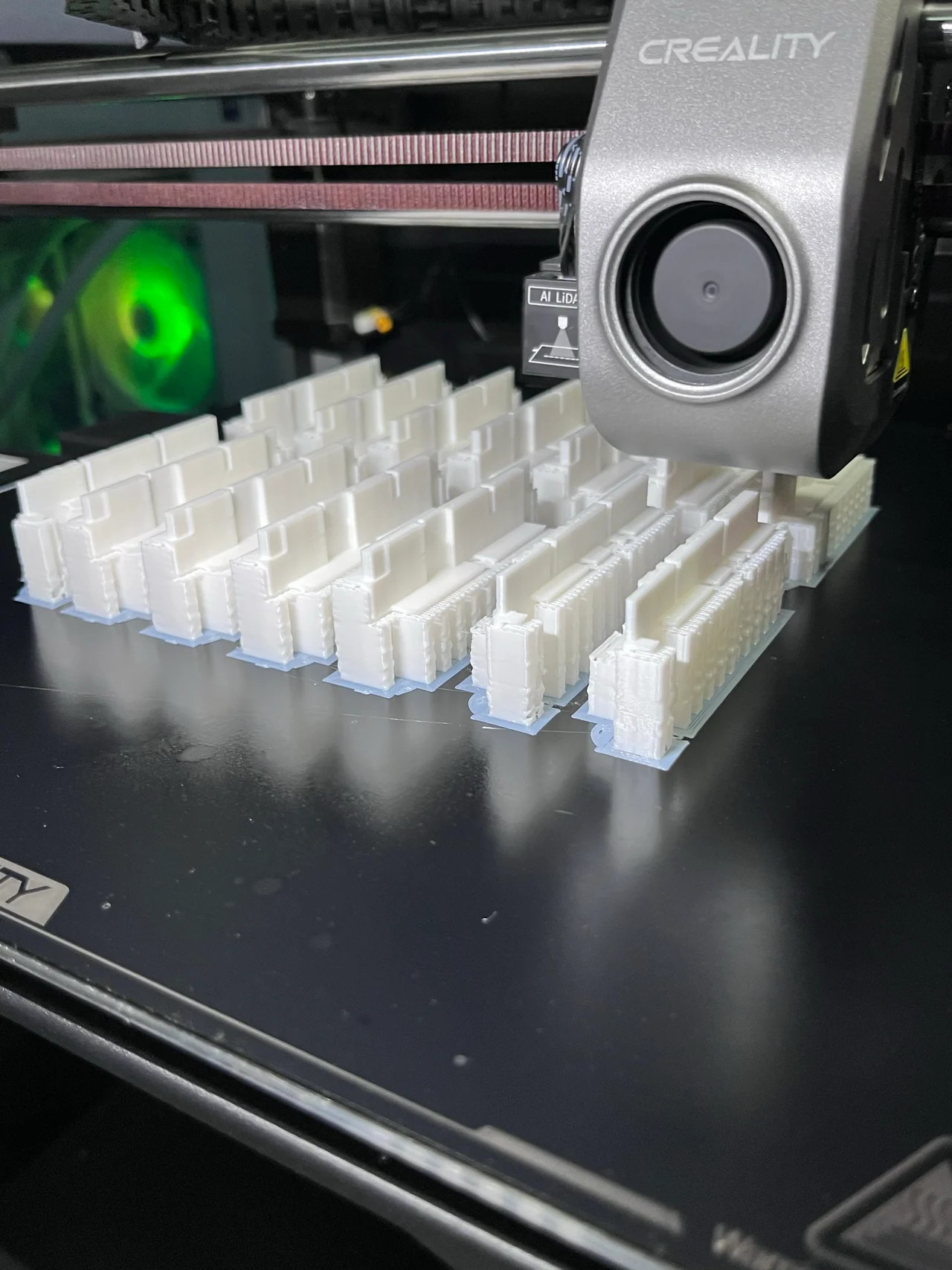 Cabezal de impresora 3D sobre filas de piezas blancas con soportes en la plataforma