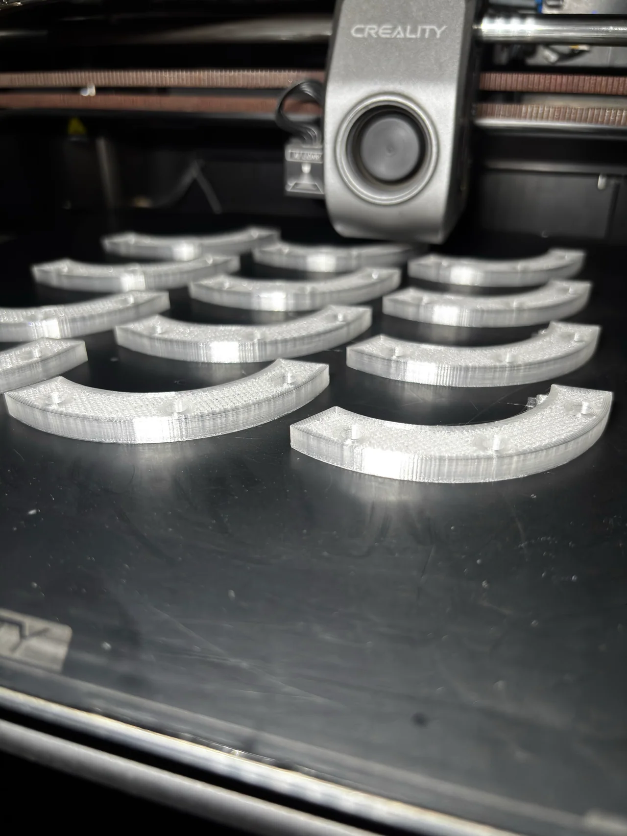 Piezas curvas con capas visibles bajo el cabezal de una impresora 3D