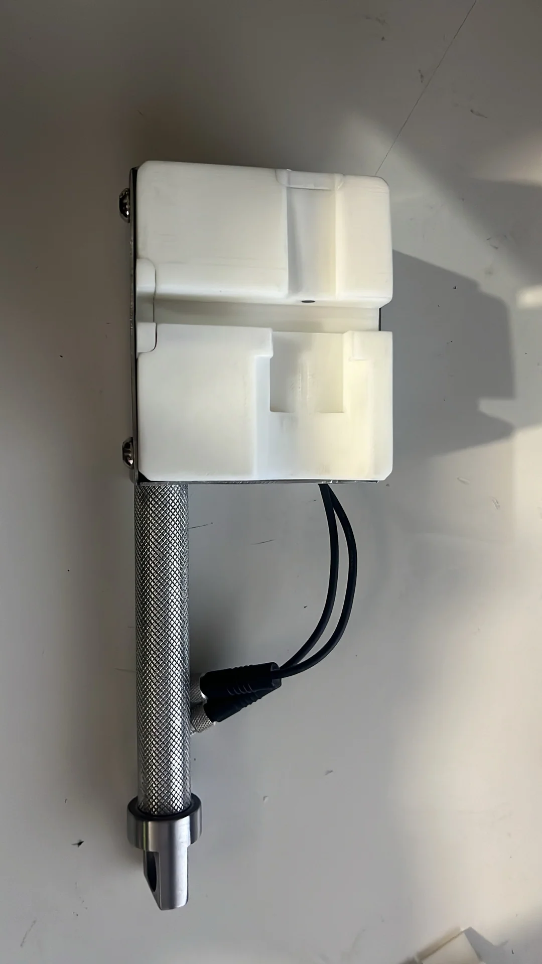Dos piezas blancas montadas sobre un soporte con mango metálico y cables